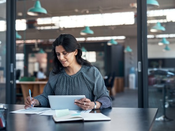 büro-arbeitssituation-schreiben-dokumente Eine Mitarbeitende bearbeitet einen Ordner mit Dokumenten und schreibt etwas hinein