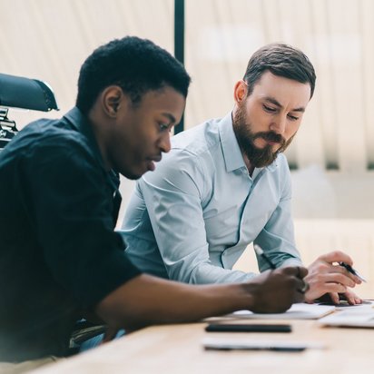 Zwei Männer arbeiten gemeinsam am Laptop in einem modernen Büro