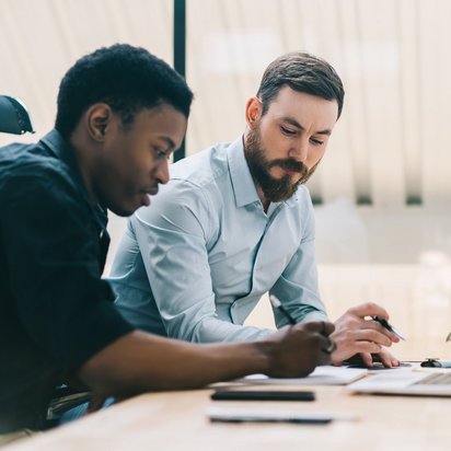 Zwei Männer arbeiten gemeinsam am Laptop in einem modernen Büro