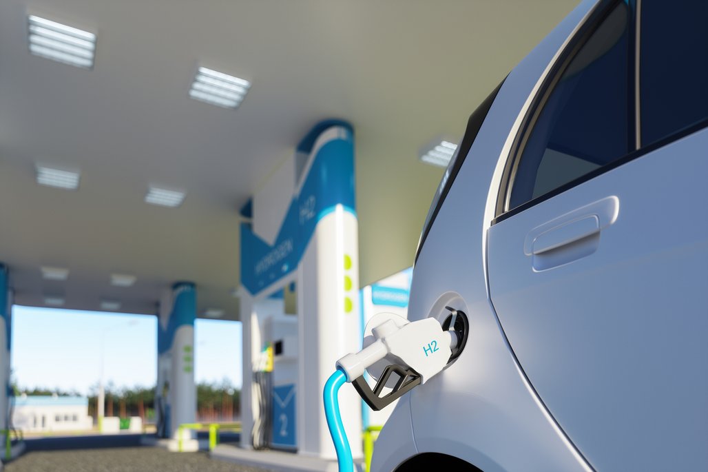 Eine Wasserstofftankstelle mit einem blauen Auto, das an einer H2-Zapfsäule aufgetankt wird.
