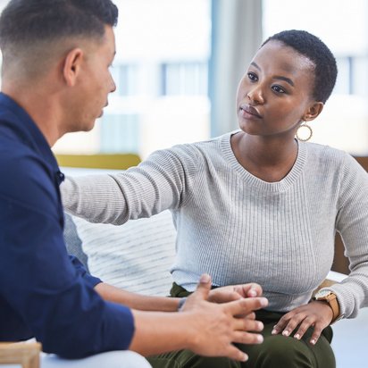 Frau spricht einfühlsam mit einem Mann in einem persönlichen Gespräch auf Augenhöhe