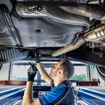  Prüfingenieur bei der Unterbodeninspektion eines Fahrzeugs an der TÜV NORD Station
