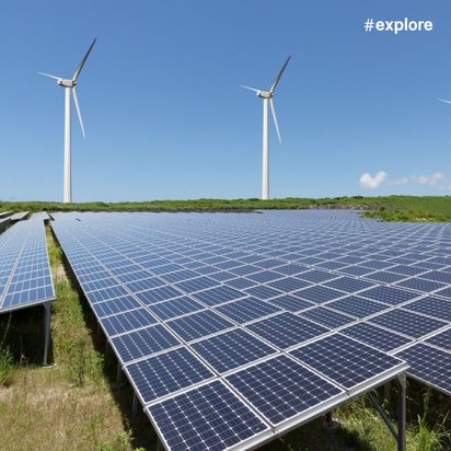 Großflächige Solaranlage mit blauen Photovoltaikmodulen im Vordergrund und vier weißen Windkraftanlagen im Hintergrund unter blauem Himmel.