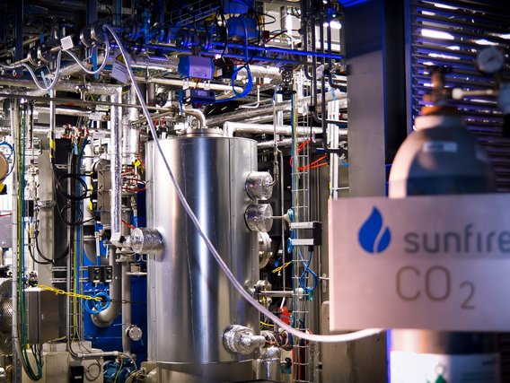 Eine komplexe Industrieanlage mit Edelstahltanks, Rohrleitungen und technischen Geräten zur CO2-Verarbeitung, erkennbar am "Sunfire CO2"-Schild rechts im Bild.