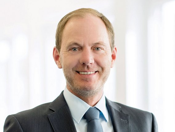 Carsten Becker mit blonden Haaren und Bart lächelt professionell in einem dunklen Anzug mit blauer Krawatte. Das Porträt zeigt ihn vor einem weißen Hintergrund in formeller Geschäftskleidung.WiederholenClaude kann Fehler machen. Bitte überprüfen Sie die Antworten. Sonnet 4