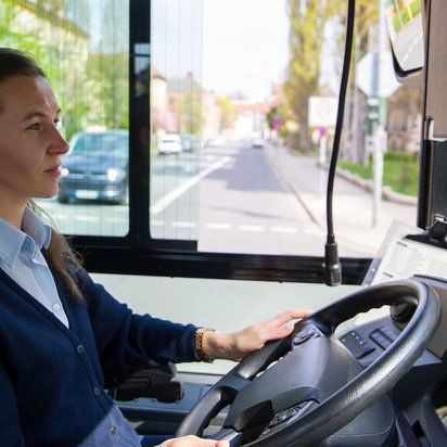 Frau fährt einen Bus und schaut auf die Straße aus dem Fenster