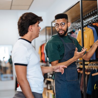 Zwei Personen in einem Bekleidungsgeschäft schauen sich zertifizierte Kleidung an.