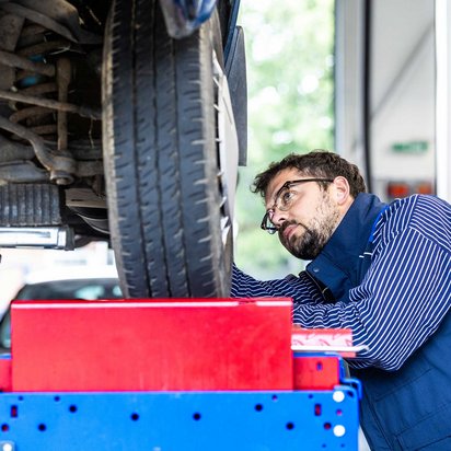 TÜV NORD Sachverständiger prüft einen Gebrauchtwagen von unten