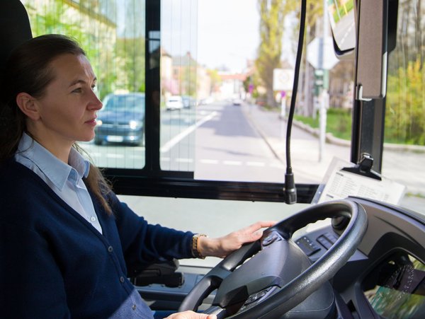 Frau fährt einen Bus und schaut auf die Straße aus dem Fenster