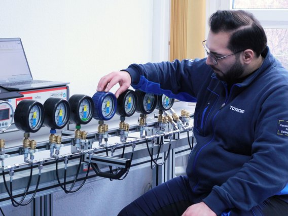 Kalibrierung von Druckmessgeräten im Labor Techniker kalibriert mehrere Druckmessgeräte an einem Prüfstand, Laptop zur Datenerfassung im Hintergrund.