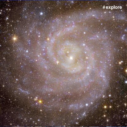 Eine detaillierte Aufnahme einer Spiralgalaxie mit deutlich sichtbaren Spiralarmen und hellem Zentrum. Die Galaxie ist von zahlreichen hellen Sternen umgeben und zeigt bläuliche und gelbliche Farbtöne.