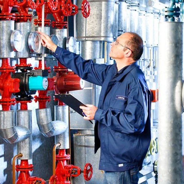 TUEV_NORD_Energiemanagementsystem TÜV NORD Experte überprüft Messgeräte und Ventile in einer Industrieanlage.