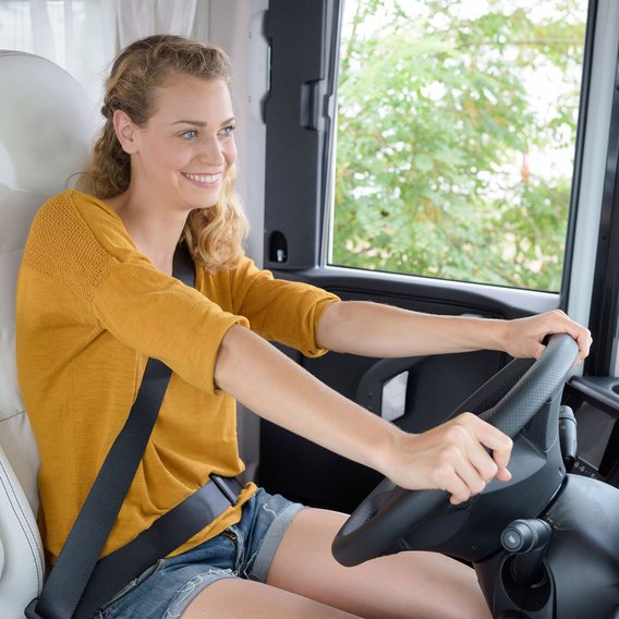 Frau am Steuer eines Wohnmobils, bereit für die Fahrt