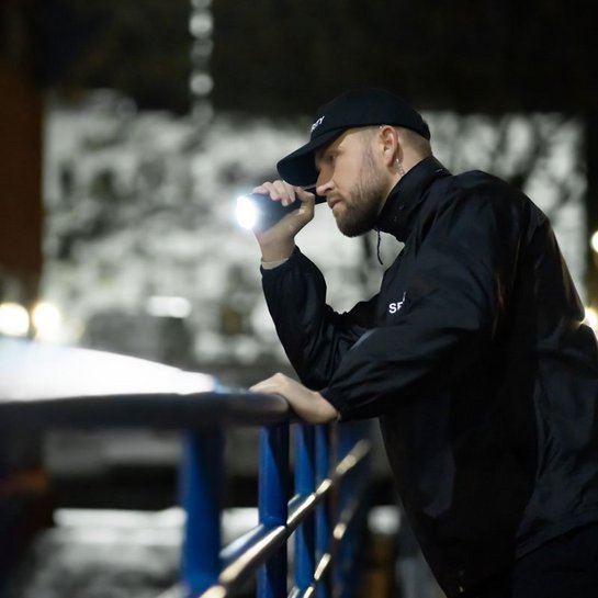 Sicherheitsmitarbeiter bei nächtlicher Patrouille mit Taschenlampe