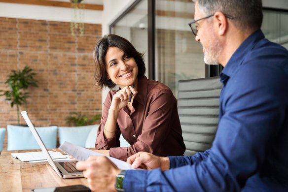 Zwei Personen im Gespräch bei einem Business-Meeting mit Laptop und Unterlagen