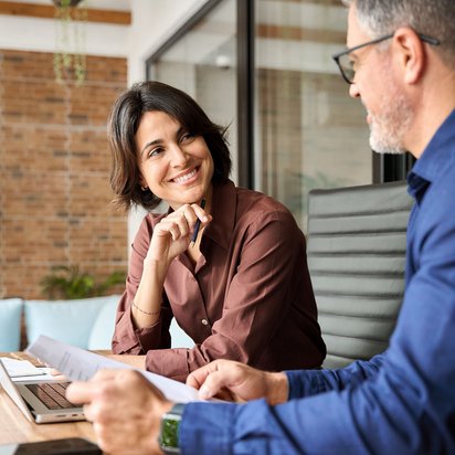 Zwei Personen im Gespräch bei einem Business-Meeting mit Laptop und Unterlagen