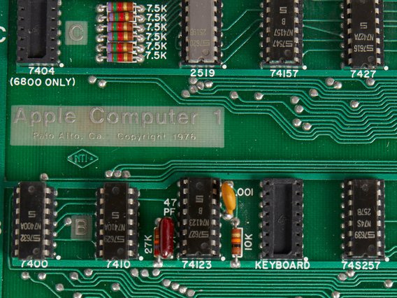 Eine Apple Computer 1 Platine von 1976, die das grüne PCB mit sichtbaren integrierten Schaltkreisen, Widerständen und der Aufschrift "Apple Computer" zeigt.
