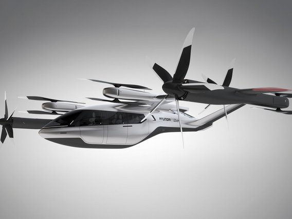 Ein weißes Flugtaxi der Marke Hyundai mit acht Rotoren und stromlinienförmigem Design vor grauem Hintergrund.