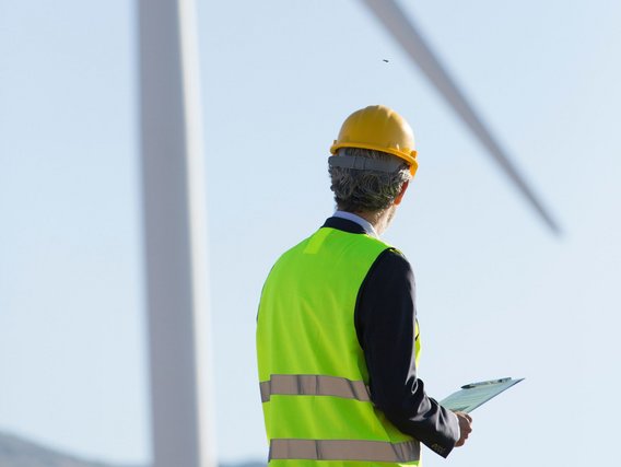 An engineer is observing a wind turbine.