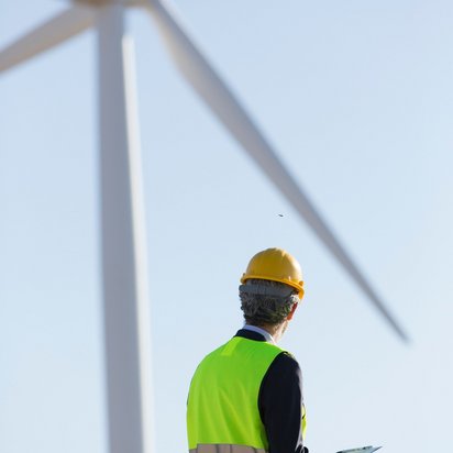 An engineer is observing a wind turbine that generates green electricity.