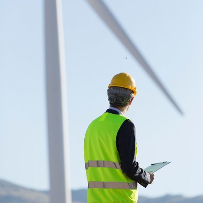 Ein Ingenieur beobachtet eine Windkraftanlage mit der Ökostrom produziert wird.