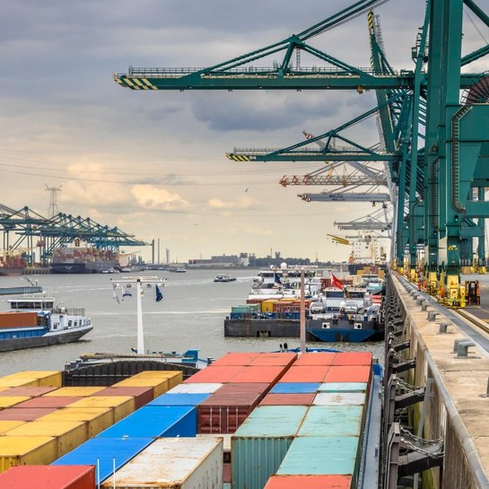 Containerschiffe und Verladekräne in einem modernen Containerhafen mit maritimer Infrastruktur.