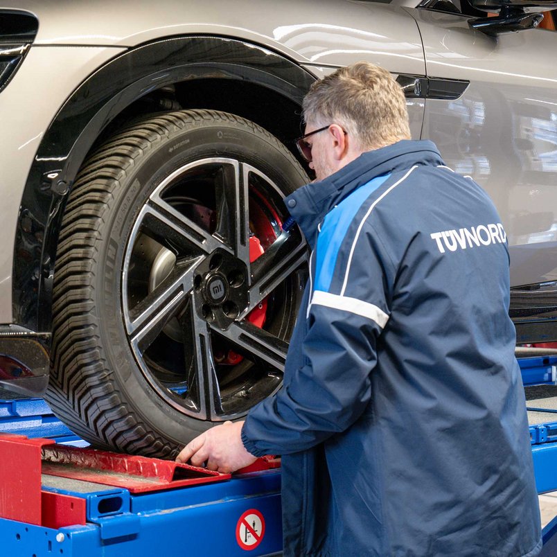 TÜV NORD Prüfer kontrolliert Rad und Bremsanlage eines importierten Fahrzeugs auf der Hebebühne im Rahmen des Datenblattservice.