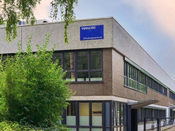 Außenansicht des TÜV NORD Schulungszentrums in Hamburg, ein modernes Gebäude mit großen Fenstern und einem blauen Schild.
