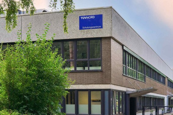 Außenansicht des TÜV NORD Schulungszentrums in Hamburg, ein modernes Gebäude mit großen Fenstern und einem blauen Schild.