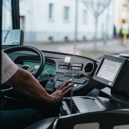Busfahrer bedient Armaturenbrett und Fahrkartenautomat in einem modernen Linienbus