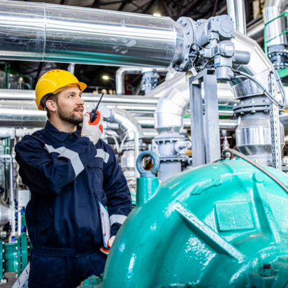 Techniker in Schutzkleidung prüft industrielle Anlage.