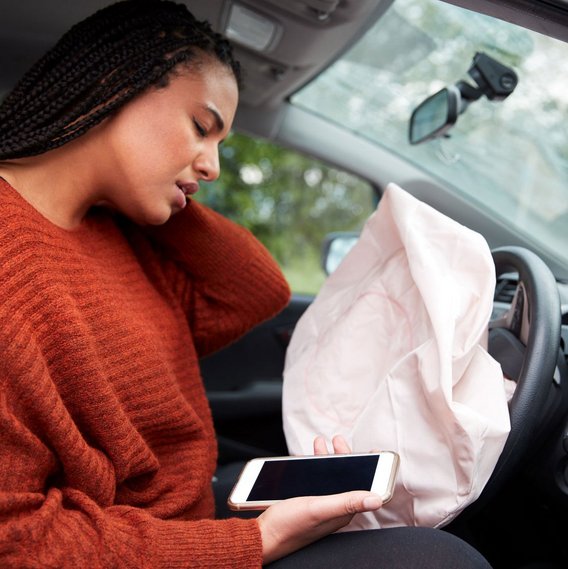 Frau im Auto nach einem Unfall mit ausgelöstem Airbag