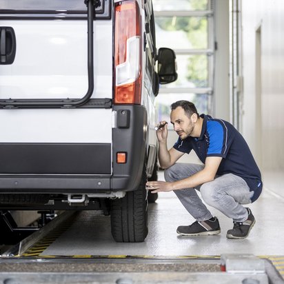 Prüfingenieur inspiziert die Reifen eines Wohnmobils an einer TÜV NORD Station