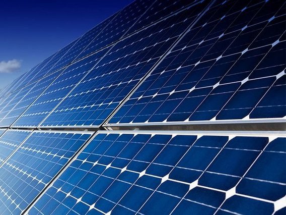 Das Bild zeigt eine Photovoltaikanlage, die von der Sonne angestrahlt wird.