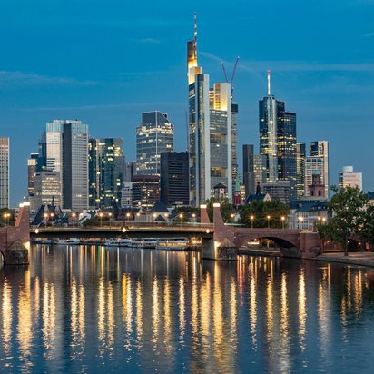 Standort Frankfurt – TÜV Nord in der Finanzmetropole Frankfurt Skyline bei Nacht mit Brücke und Wolkenkratzern