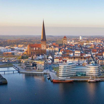 Luftaufnahme der Stadt Rostock mit Blick auf historische Gebäude und moderne Architektur am Wasser