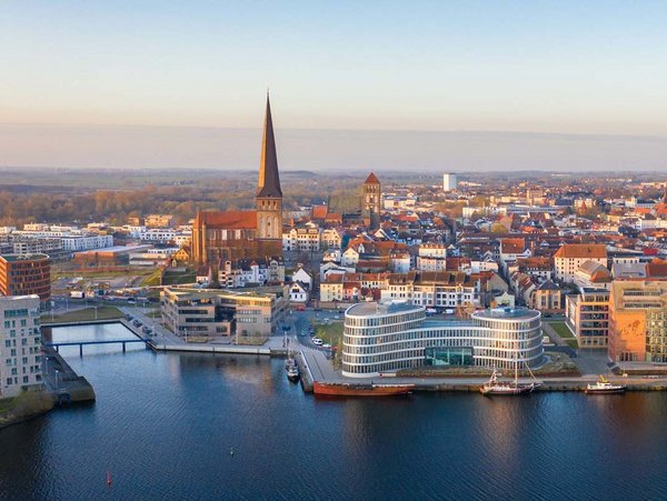 Luftaufnahme der Stadt Rostock mit Blick auf historische Gebäude und moderne Architektur am Wasser