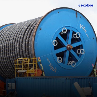 Riesige blaue Kabeltrommeln auf einem Spezialschiff transportieren hunderte Kilometer Seekabel für die Offshore-Verlegung.