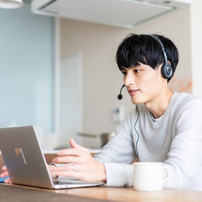 Junger Mann mit Headset nimmt an einem Online-Meeting über Laptop teil.