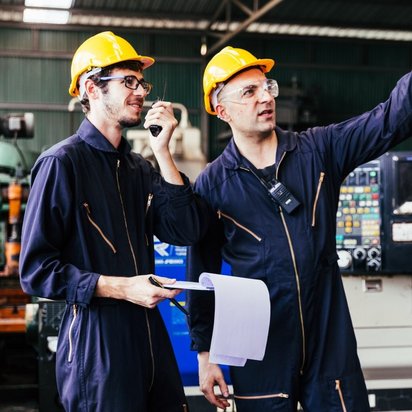 Zwei Mitarbeiter beobachten und koordinieren die Produktion.