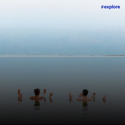 Ein Mann und eine Frau sitzen im Meerwasser, während ihre Hände und Füße aus dem Wasser ragen.