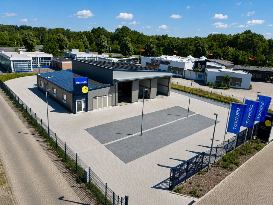 Luftaufnahme der TÜV NORD Station Wolfenbüttel-Halchter mit moderner Prüfhalle und Kundenparkplätzen.