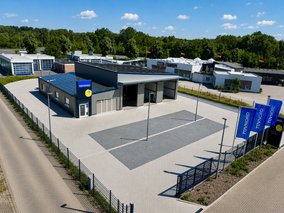Luftaufnahme der TÜV NORD Station Wolfenbüttel-Halchter mit moderner Prüfhalle und Kundenparkplätzen.