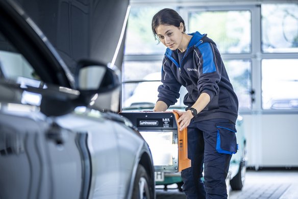 TÜV NORD Mitarbeiterin führt einen Lichttest bei einem Fahrzeug durch