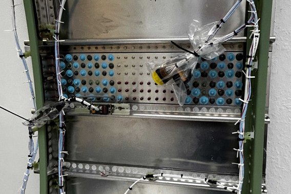 Ein Metallrahmen mit Kabeln und elektronischen Komponenten, die sorgfältig angeordnet sind. Die Szene zeigt die Komplexität der Flugzeugelektrik in der Luftfahrttechnik.