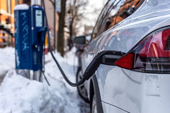 Weißes Auto steht bei Schnee an einer Ladestation und lädt