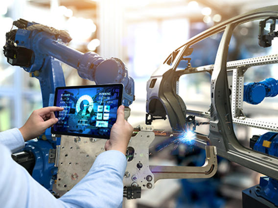Mitarbeiter steuert über Tablet einen Industrieroboter in der Automobilproduktion – Digitalisierung und Qualitätsmanagement nach VDA-Standards