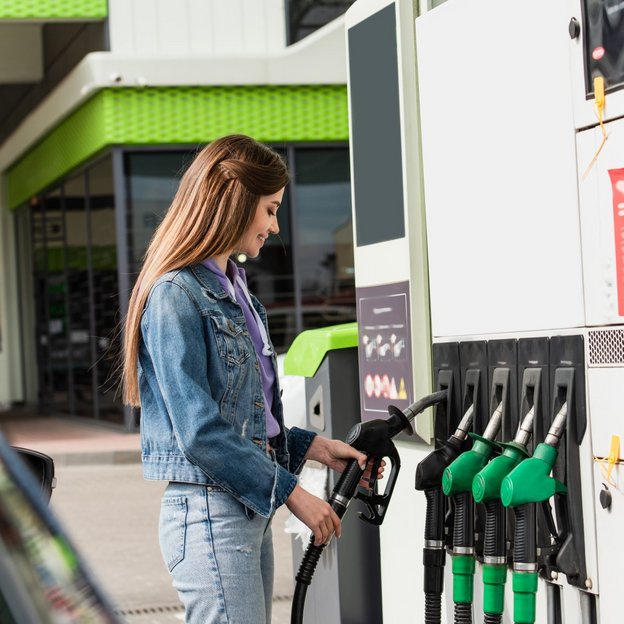 Frau betankt ihr Auto an einer Tankstelle