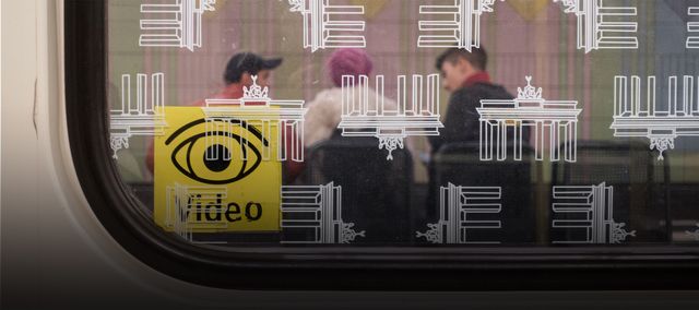 Ein Fenster einer Berliner U-Bahn mit einem Aufkleber, der auf Videoüberwachung hinweist.