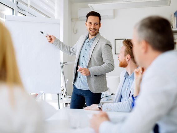 Mann präsentiert vor einer Gruppe in einem hellen Besprechungsraum an einem Flipchart
